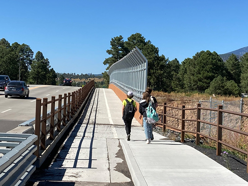 People wlaking on a path next to a highway